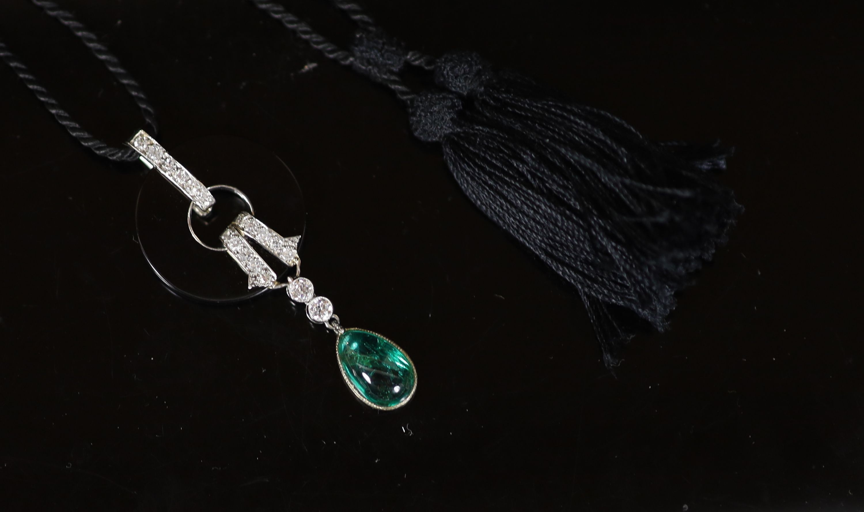 A French Art Deco style platinum, black onyx, diamond and pear cut cabochon emerald set drop pendant, on a black fabric cord